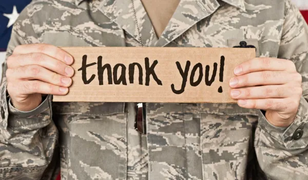 Military service member holding thank you sign