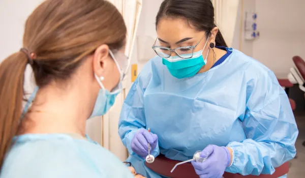 Dental Assistant in scrubs calms patient during procedure with dentist