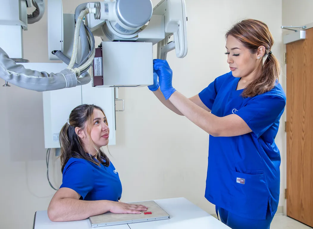 A radiology tech adjusts an x-ray machine on a patient's hand.