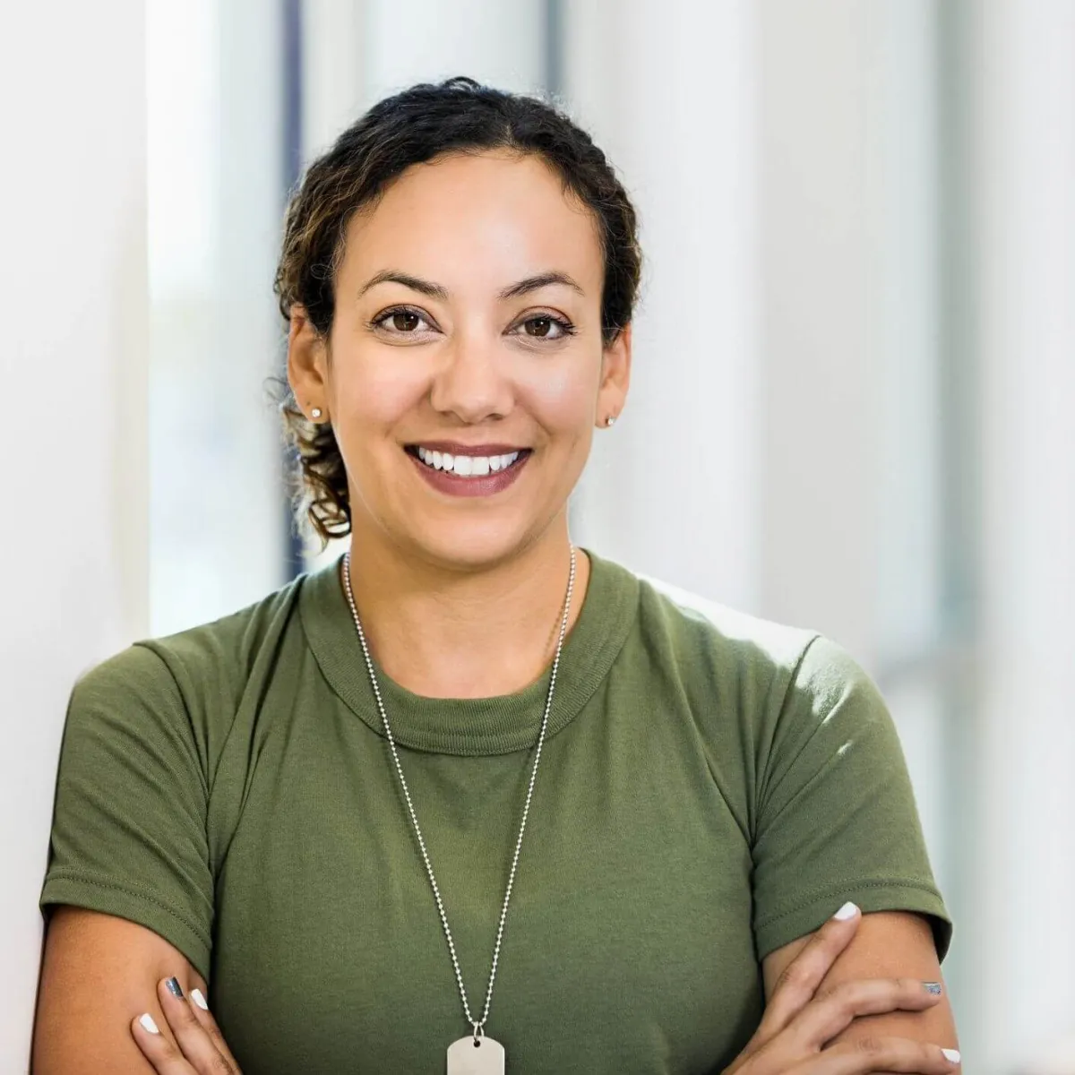 A portrait of a smiling woman wearing military dog tags, representing the military spouses and service members eligible for the Concorde military tuition support program.