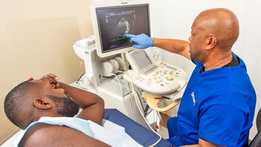 Cardiac sonographer with patient points to image on screen.