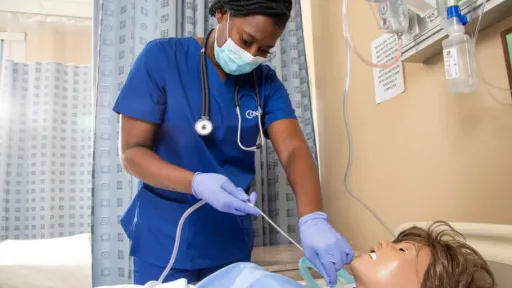 Nursing student performing suctioning procedure on training manikin in lab