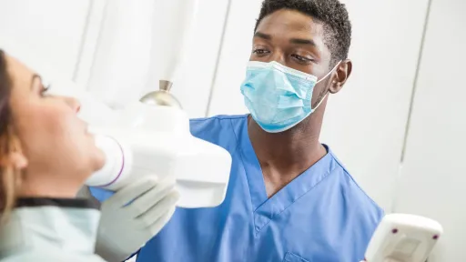 Registered Dental Assistant in Extended Functions (RDAEF) preparing a patient for dental X-ray with handheld imaging device