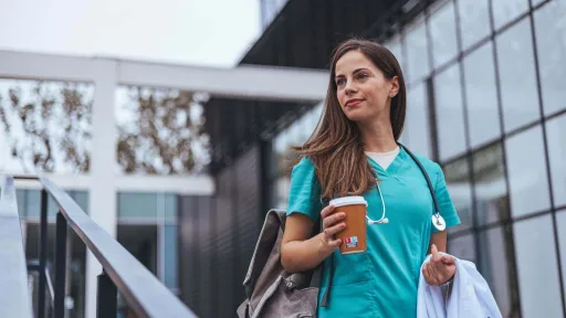 Traveling medical assistant in scrubs on the go with a cup of coffee and backpack.
