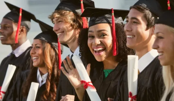 Smiling graduates holding diplomas and degrees