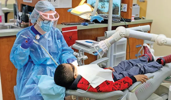 A dental hygienist performs a routine cleaning on young male patient.
