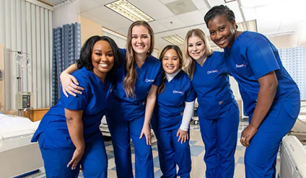 5 smiling LPN graduates from Concorde wearing their scrubs.