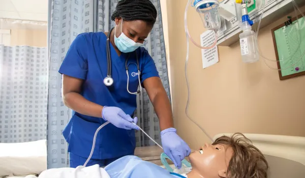 Nursing student practicing skills on a simulation mannequin.