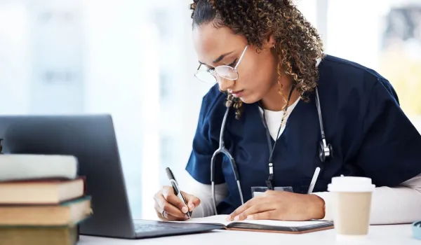 Nursing student in scrubs studying online, representing RN to BSN program and Bachelor of Science in Nursing coursework.