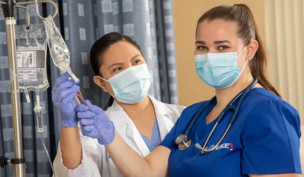 Nursing student learning to check IV fluid levels during hands-on training session