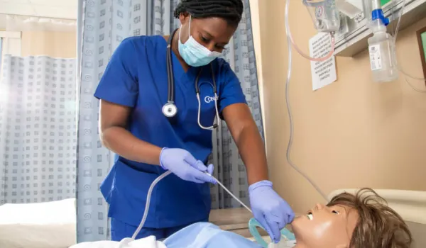 Nursing student performing suctioning procedure on training manikin in lab