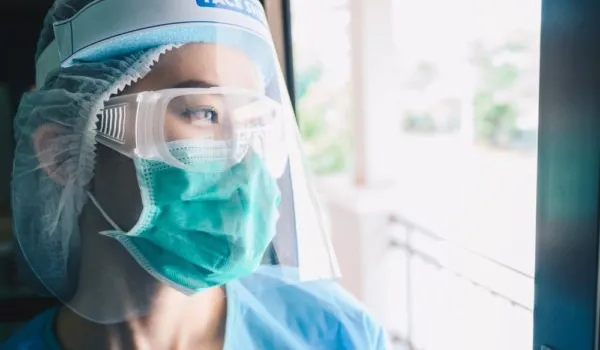 Masked Nurse looking out window