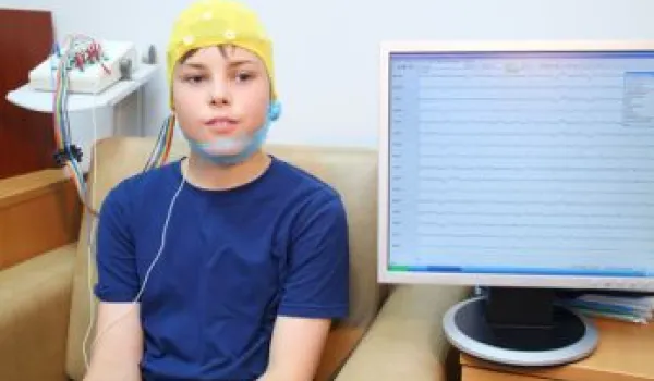 Boy in a special cap during electroencephalography next to the monitor with readings