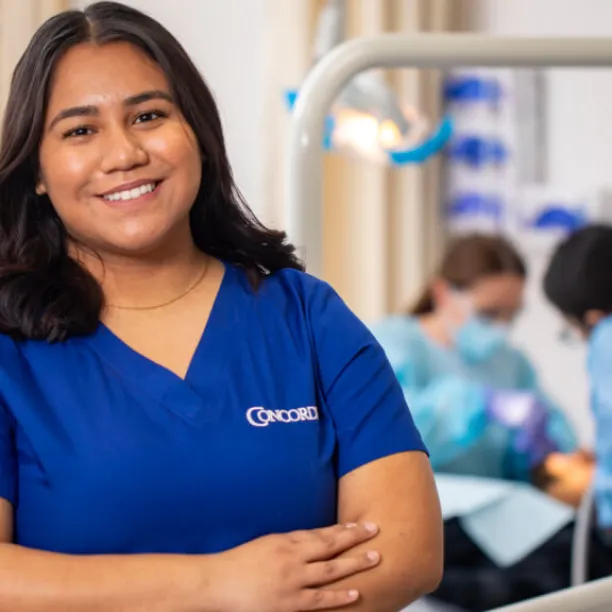 Dental Assistant in scrubs smiles with confidence