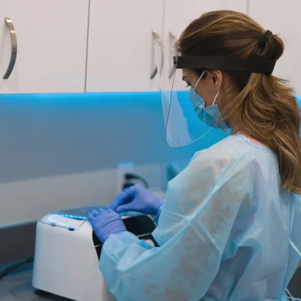 Sterile Processing Technician wearing PPE sterilizing medical equipment at the hospital.