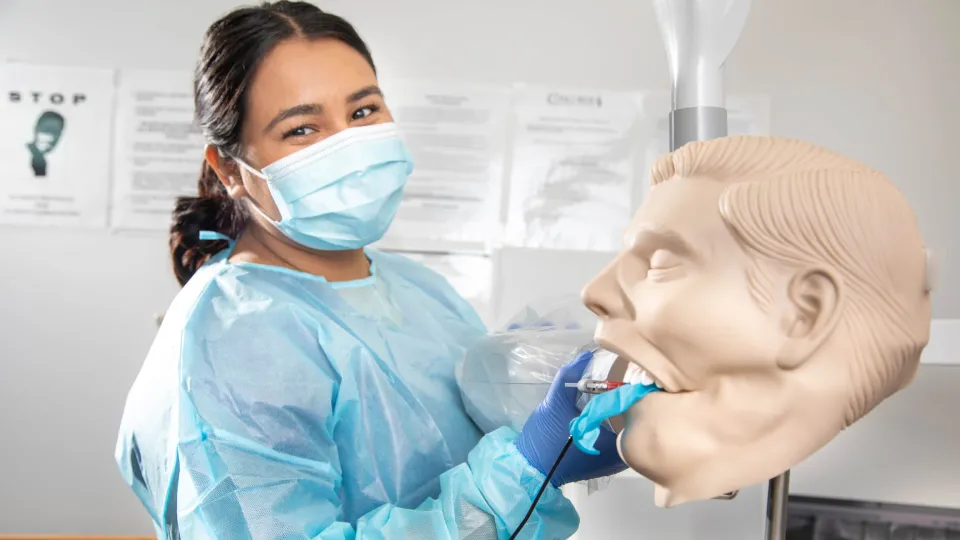 Dental Assistant cleaning the mouth of a dental manekin.