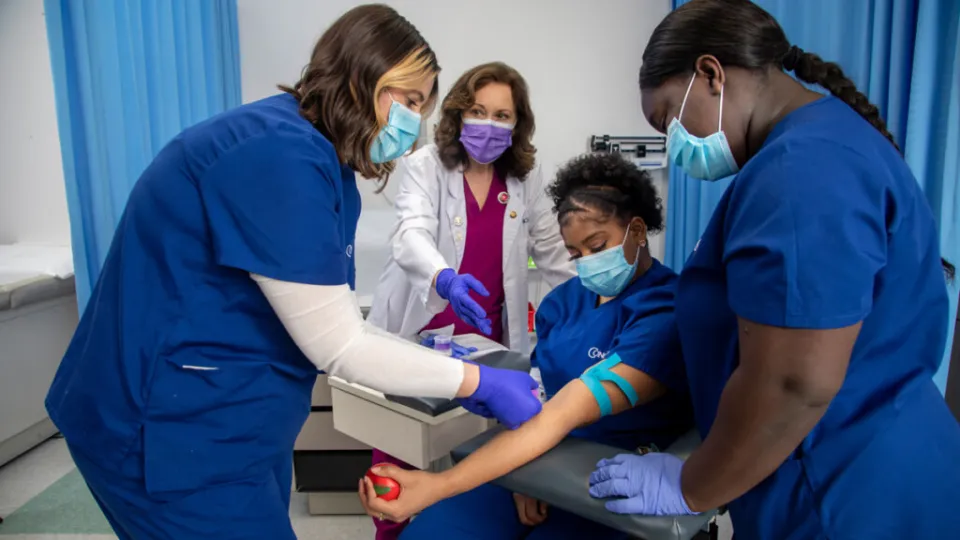 Medical assistant students practicing phlebotomy skills during hands-on training in a clinical education lab setting.
