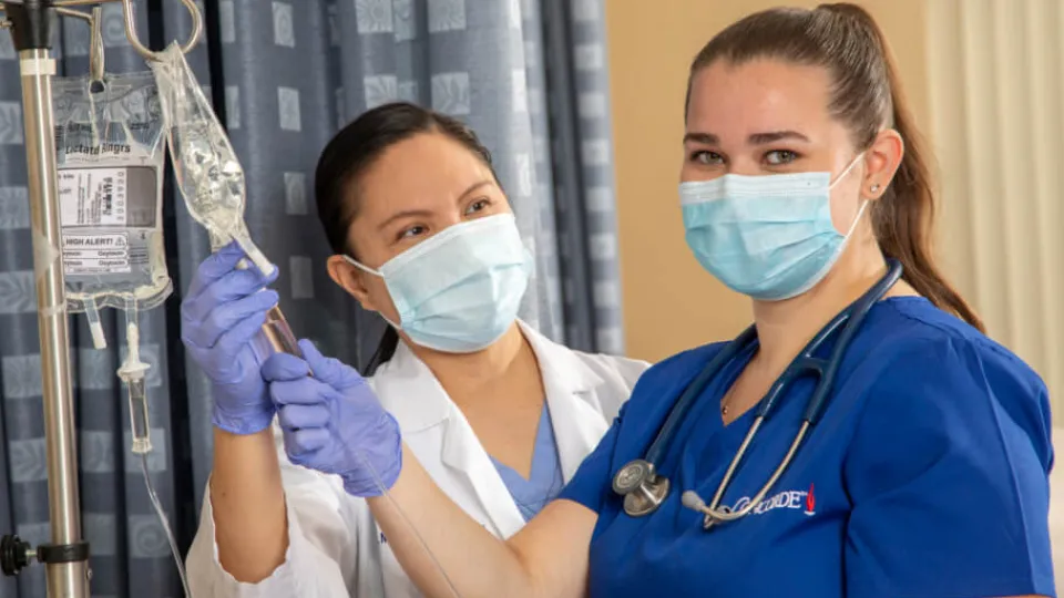 Nursing student learning to check IV fluid levels during hands-on training session