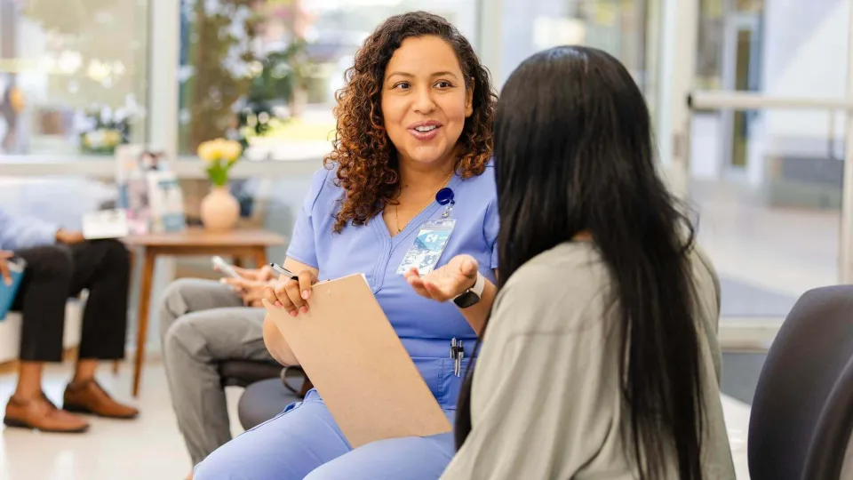 Medical office specialist speaking with patient in a clinic waiting room, highlighting the role's communication and support duties