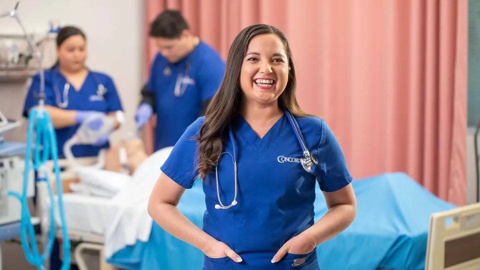 Concorde student smiling as others study respiratory therapy in the background
