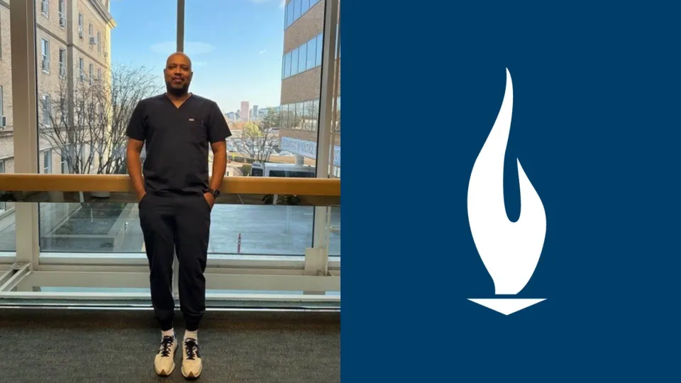 JR in navy blue scrubs standing proudly in the hallway of a hospital