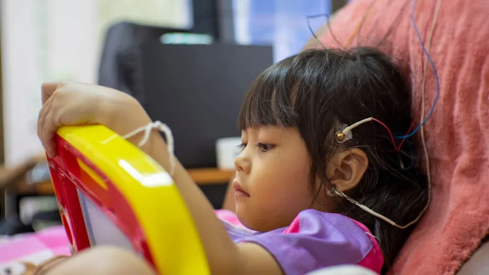 A Neurodiagnostic Technologist performs an electroencephalogram (EEG) on a young child, placing electrodes on the scalp as part of their clinical training for a key neurodiagnostic course.