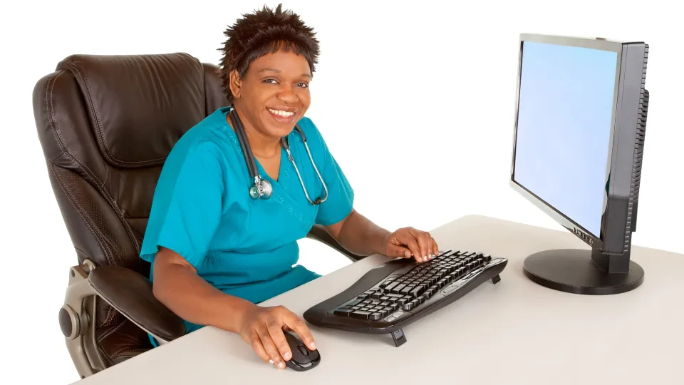 African American Nurse Smiling at Camera While Sitting at Desk medical office administrator