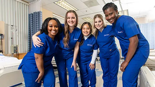 5 smiling LPN graduates from Concorde wearing their scrubs.