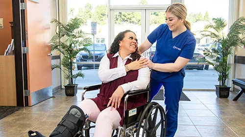 A practical nurse comforts a patient in a wheel chair.