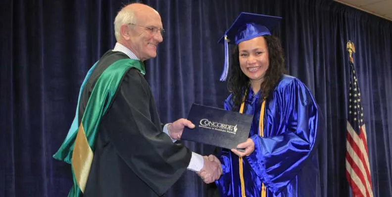 A Concorde graduate receiving her certification at a graduation ceremony.